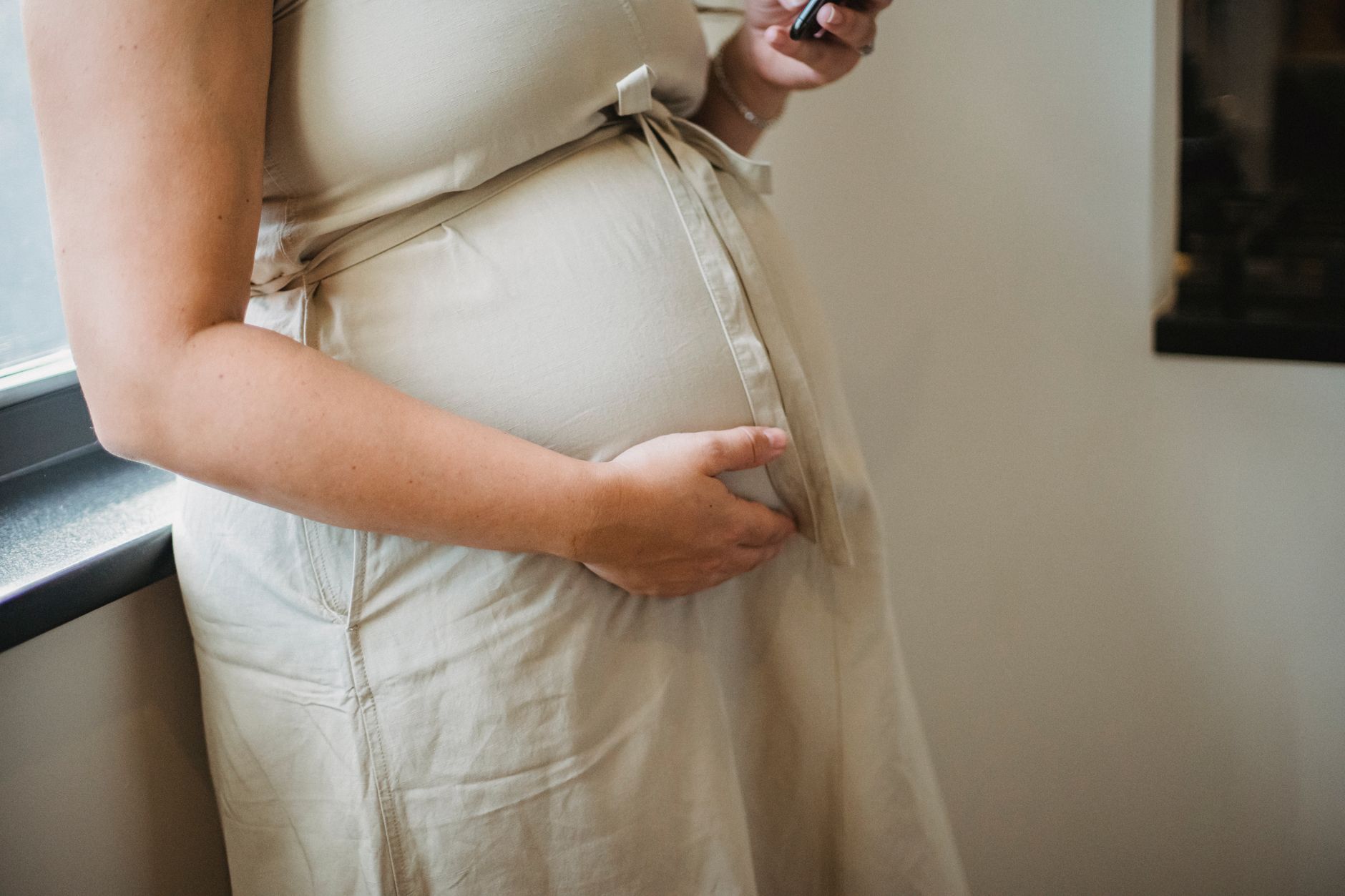 Pregnant woman gently touching her face, illustrating gentle skincare during pregnancy.