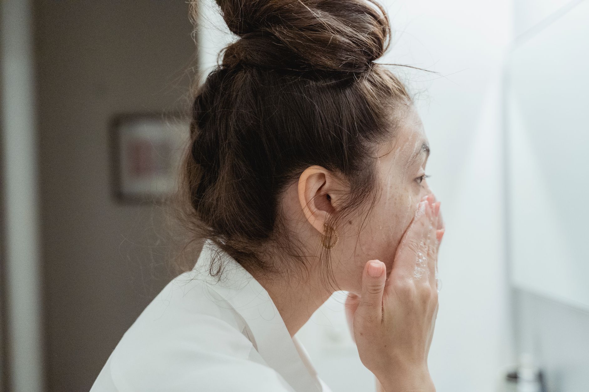 A person gently washing their face with a lather of cleanser